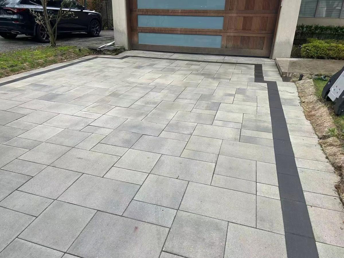 Interlock driveway with a contrasting paver border leading to a modern garage