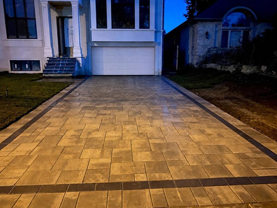 Warm-toned interlock driveway lit at dusk in front of a home