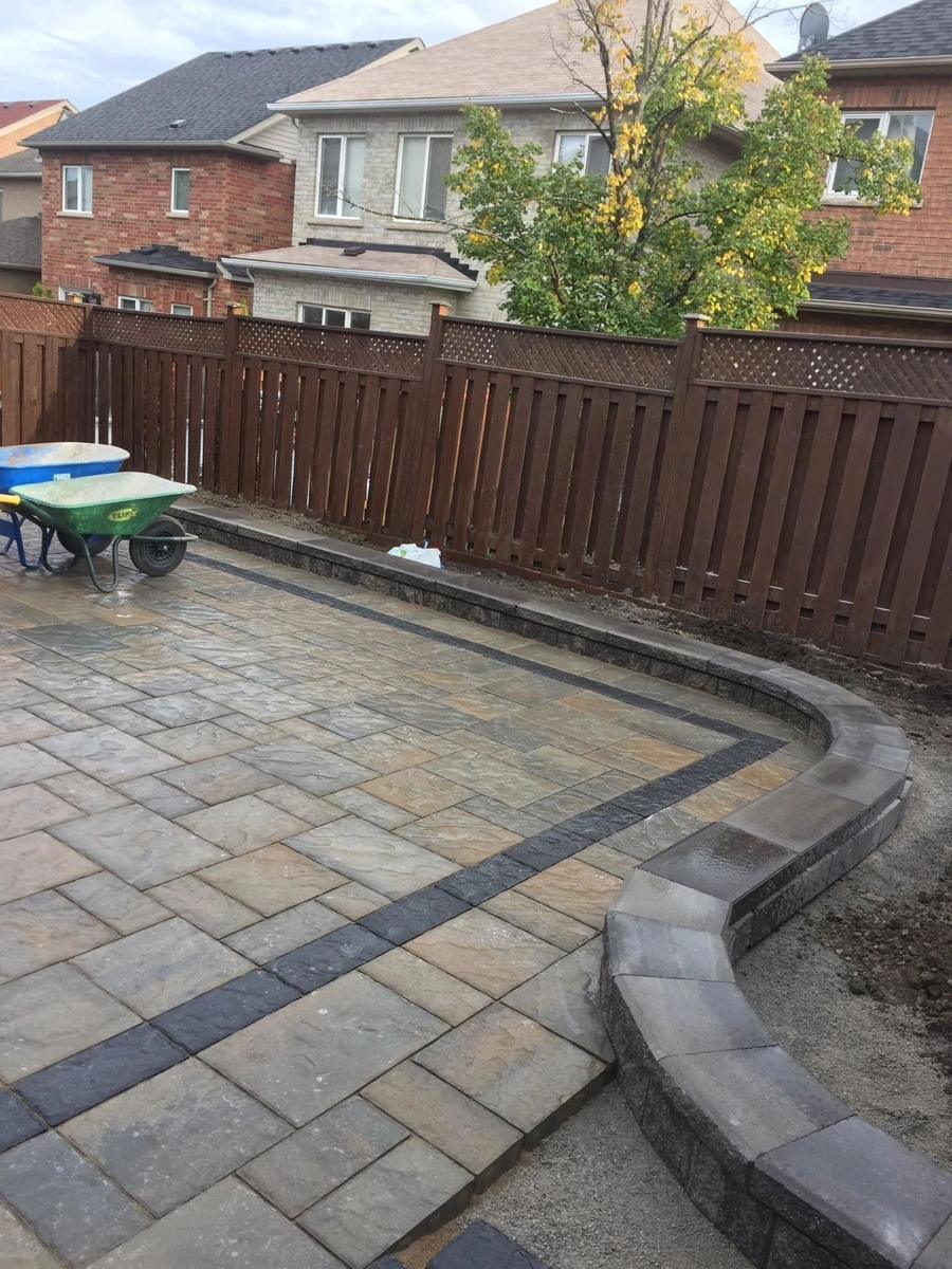 Patio in warm-toned slabs with a curved raised border wrapping the corner