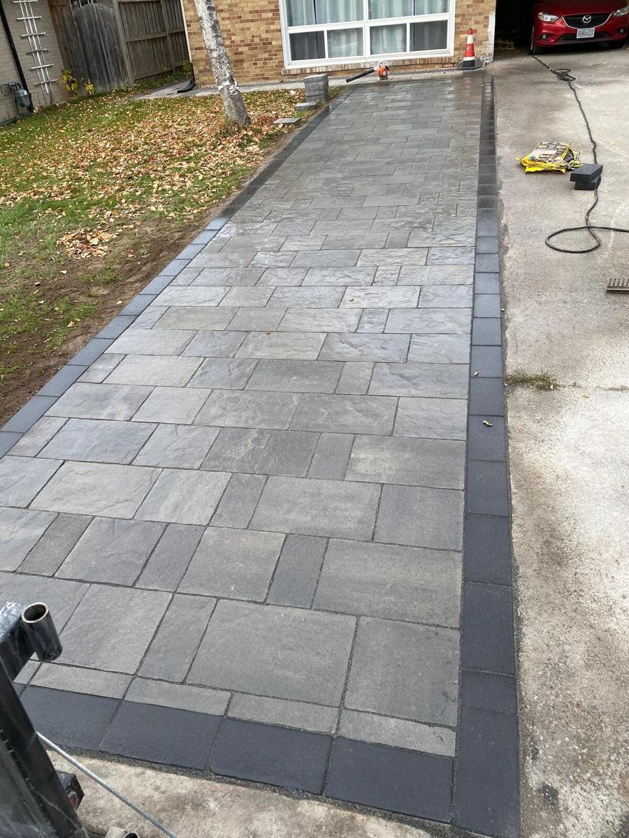 Grey paver walkway laid the full length of a driveway and edged in charcoal