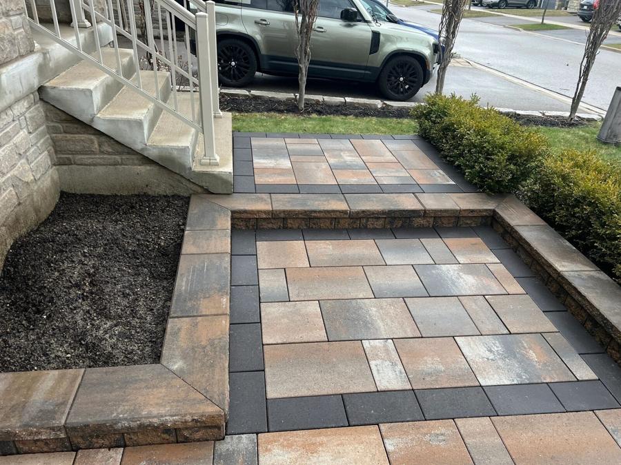 Front walkway in banded pavers leading to steps and a fresh planting bed