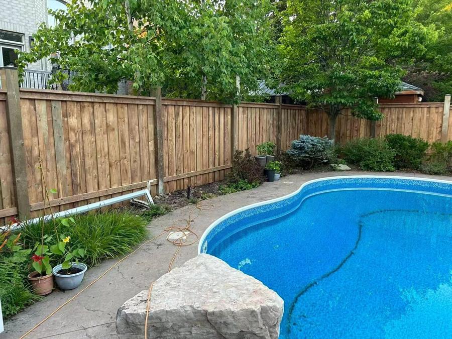 Curved swimming pool with a stone-paved surround, boulder and garden beds