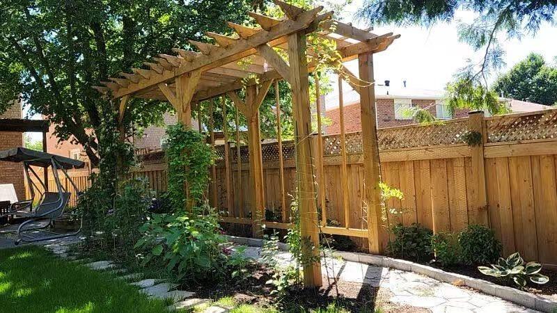 Cedar pergola over a flagstone path, framed by climbing vines, hostas and a planted border