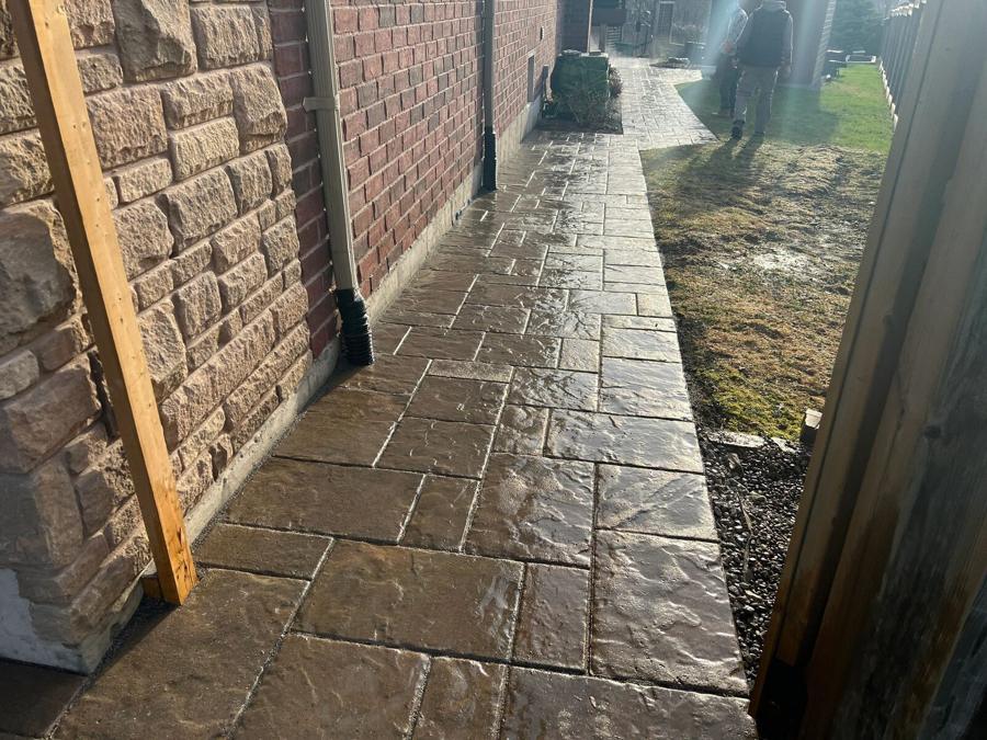 Textured stone-look walkway running alongside a brick home