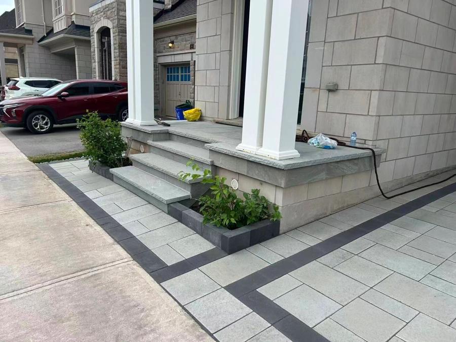 Front porch with white columns, pale stone steps and a banded paver landing