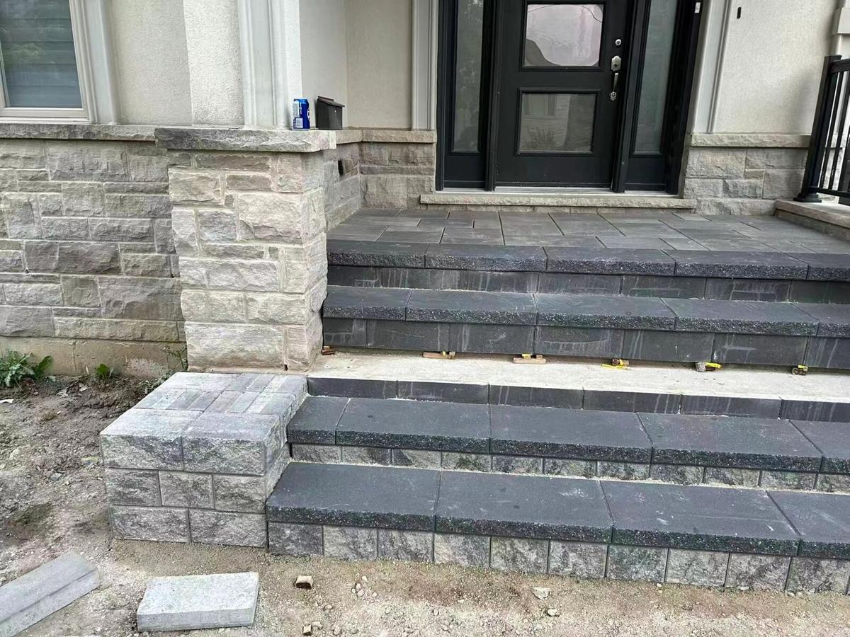 Front entrance steps with dark treads beside a block masonry porch wall
