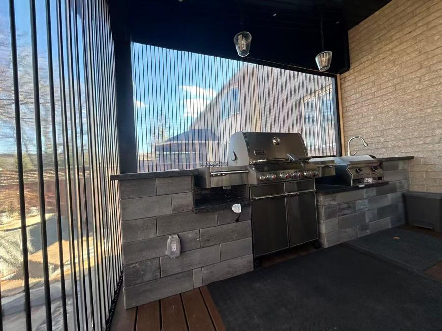 Built-in barbecue and sink in a block-faced outdoor kitchen under a covered structure