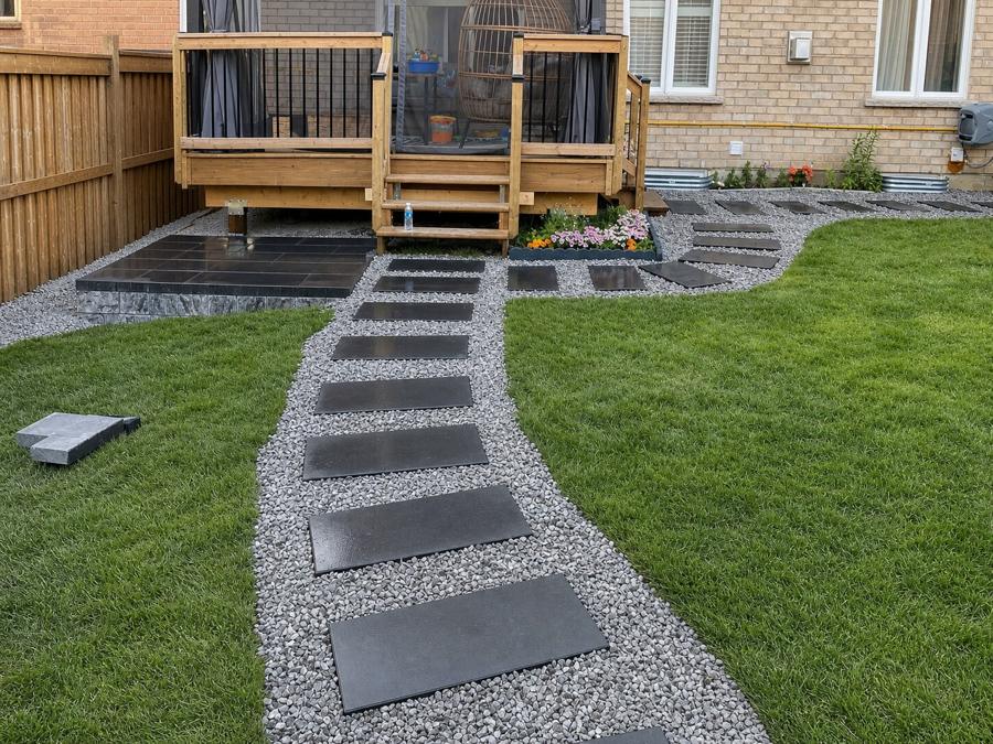 Cedar deck overlooking a dark stepping-stone path and fresh sod lawn