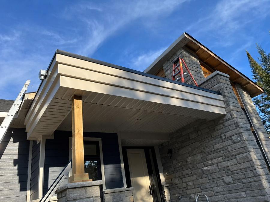 Covered porch roof structure against a blue sky