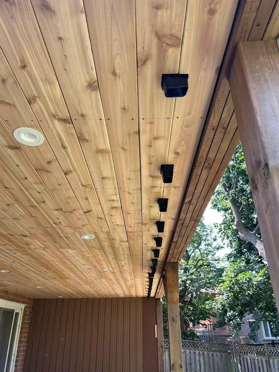 Cedar-clad ceiling of a covered porch with recessed lighting and an exposed beam