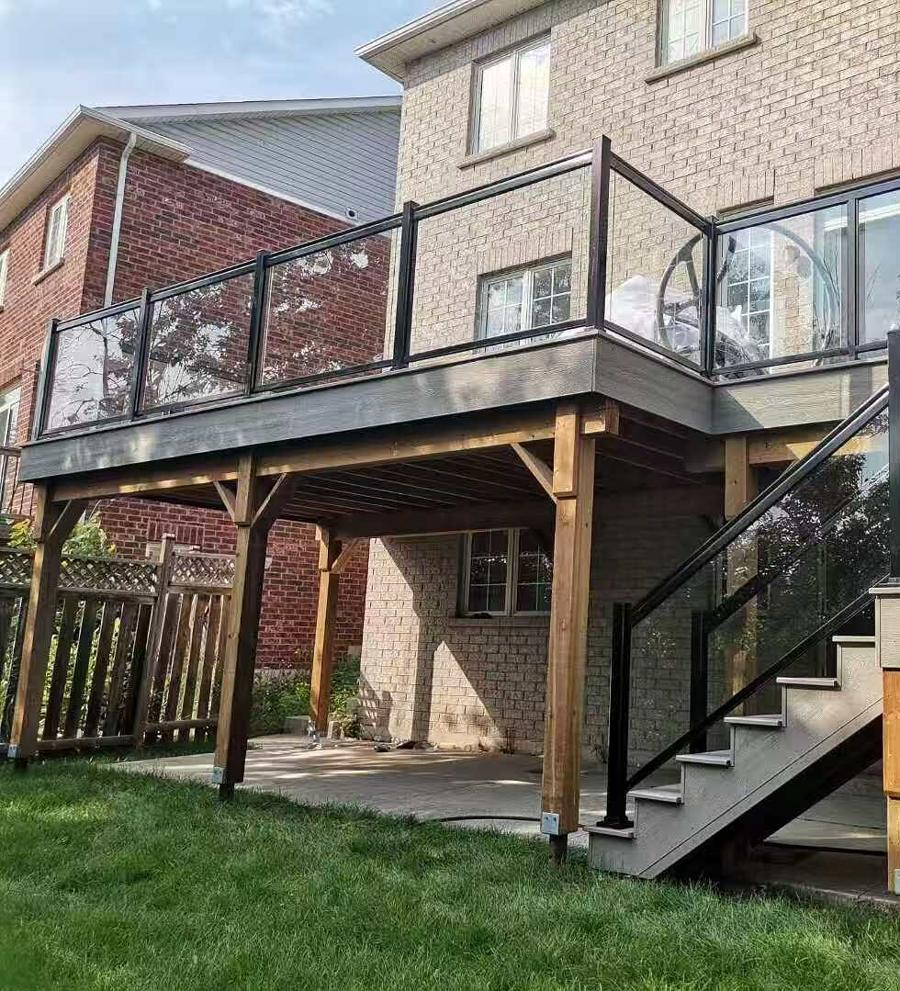 Raised deck with a glass railing and cedar posts, with a sheltered sitting area underneath