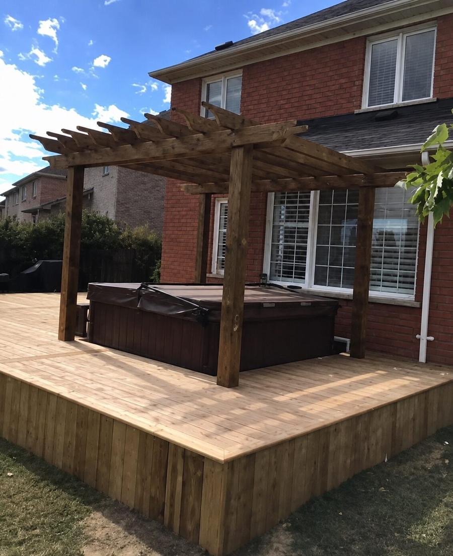 Cedar pergola over a hot tub on a raised deck against a brick house