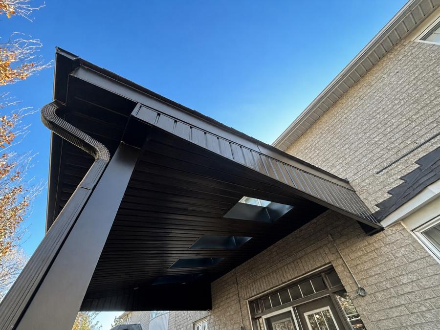 Dark patio cover with skylights and a gutter, carried on a square support post